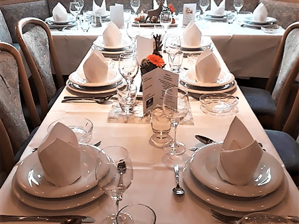 Elegantes Restaurant mit festlich gedecktem Tisch, weiße Tischdecken, geschmackvolle Dekoration.