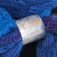 Taimi Design Breiter, gravierter Silberring mit feinem Muster umschließt einen blau-violetten Strickschal.