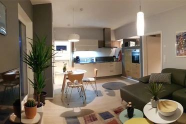 Moderne Wohnküche mit Holzfußboden, Esstisch, Ecksofa, Küchenzeile und stilvoller Beleuchtung.
