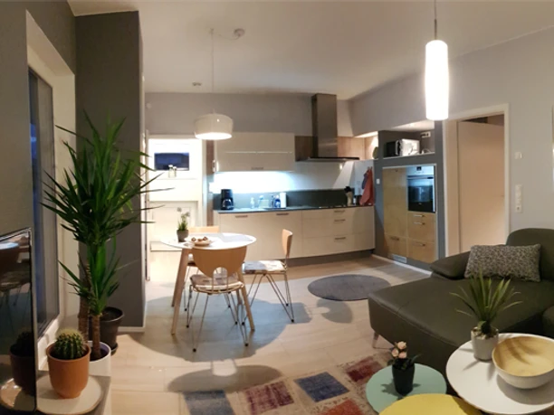 Moderne Wohnküche mit Holzfußboden, Esstisch, Ecksofa, Küchenzeile und stilvoller Beleuchtung.