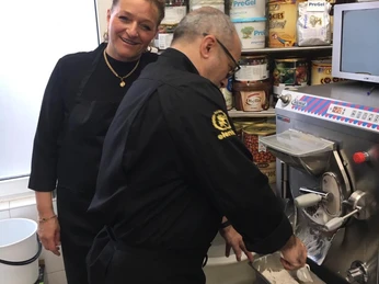 Gelateria Capri_Inhaber Zwei Personen in einer Eisdiele bereiten Speiseeis an einer Eismaschine zu, umgeben von Eiszutaten.