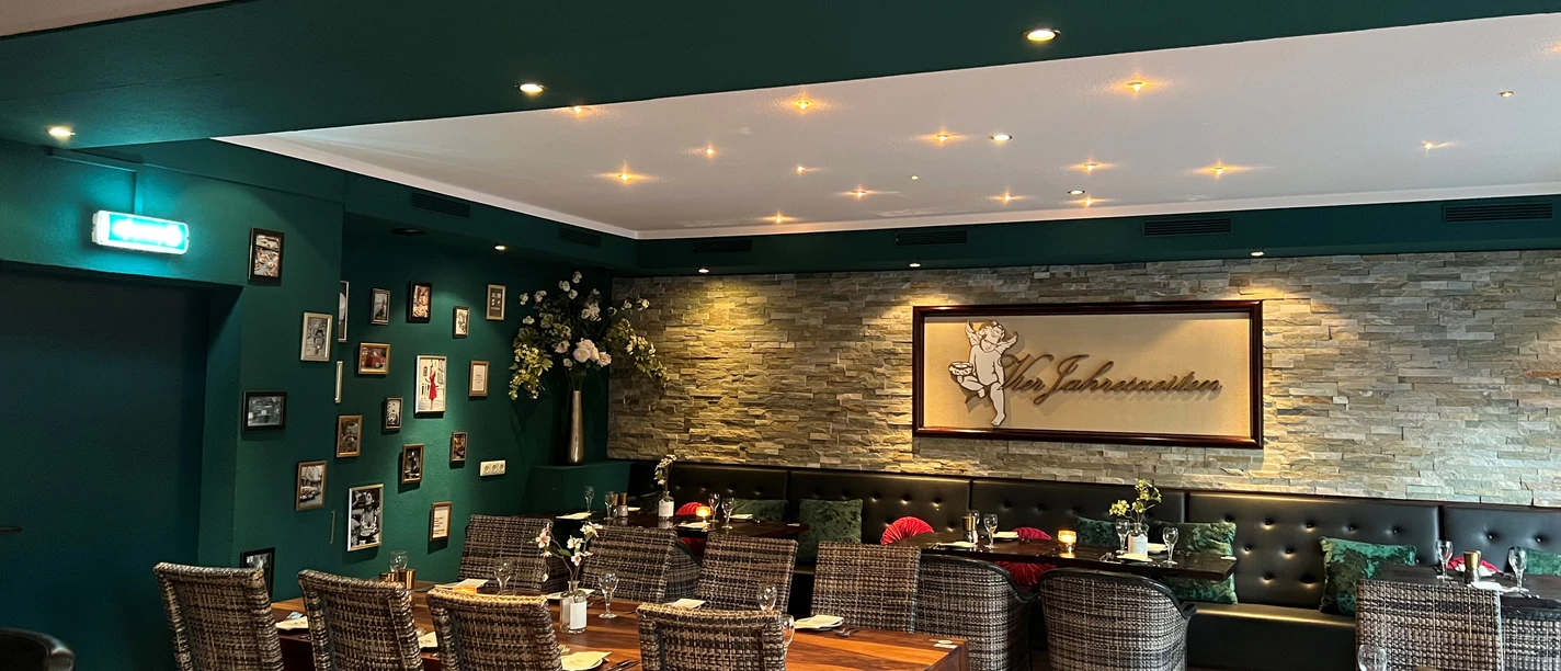 Cozy restaurant with rattan chairs, decorative stone wall and set tables for guests.