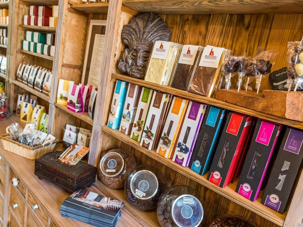 Shelves with colorful chocolate packaging, chocolate lollipops and baskets in a wooden store; warm, inviting atmosphere.