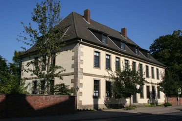 Das zweigeschossige historische Gebäude repräsentiert klassische Architektur mit hohen Fenstern.
