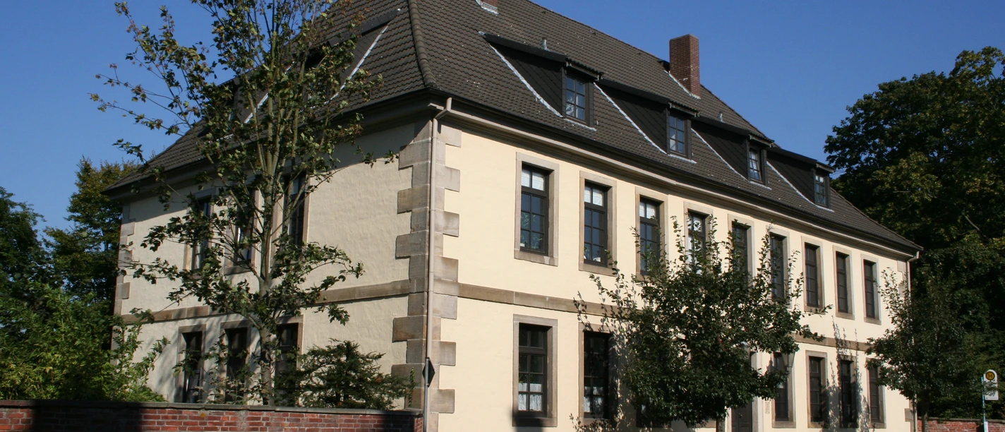 Das zweigeschossige historische Gebäude repräsentiert klassische Architektur mit hohen Fenstern.