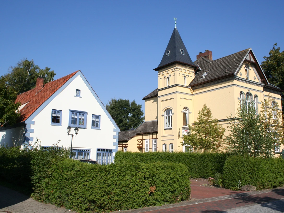 Historisches Rathausensemble mit gelbem Turmgebäude und benachbartem weißen Fachwerkhaus.