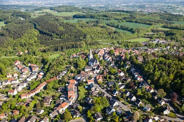 Stadt Oerlinghausen – Fotograf Patrick Piecha Luftaufnahme einer grünen Hügelstadt mit vielen Häusern, einer Kirche und umgeben von Wäldern.