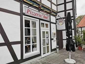 Außenansicht der Pizzeria "due" mit Fachwerkcharme und markantem Eingang in einem schmucken Ort.