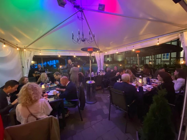 Bunte Lichter erleuchten eine gemütliche Restaurantterrasse, wo Gäste gesellig dinieren.