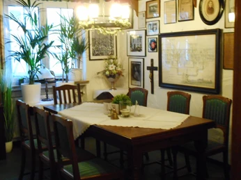 Gemütlicher Speiseraum mit Holztisch, antiken Stühlen und Wänden voller Bilder und Dekorationen.