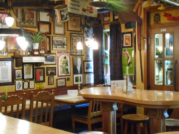 Rustikales, gemütliches Restaurant mit dekorierten Holzmöbeln, Bildern an der Wand und sanfter Beleuchtung.