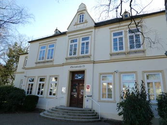 Altes Rathaus Historisches Gebäude mit drei Giebeln, symmetrischen Fenstern und einem zentralen Holzeingang.