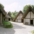 AFM_Große_Bergstadt_Runde_1.JPG Drei rekonstruierte historische Fachwerkhäuser mit Strohdächern in einem Freilichtmuseum bei Sonnenschein.