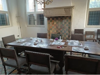Teestunde im Steinhaus Holztisch mit Teeservice und Blumen vor historischem Kamin im Steinhaus Greetsiel.