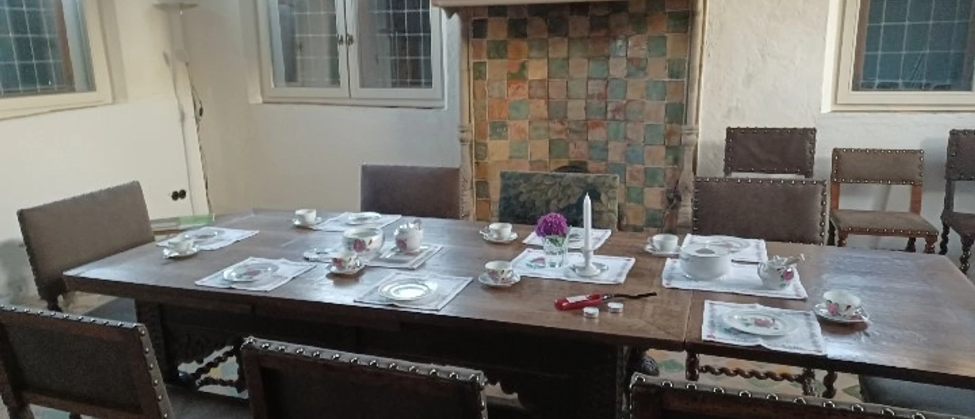 Teestunde im Steinhaus Holztisch mit Teeservice und Blumen vor historischem Kamin im Steinhaus Greetsiel.