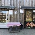 Fleischautomat am Grimberghof Zwei Automaten an einer Holzwand bieten verschiedene Waren, einer mit Fleischprodukten und außen ein Tisch.