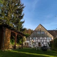 Fachwerkhaus mit Garten und Bäumen, kombiniert traditionelle Architektur und grüner Außenbereich.
