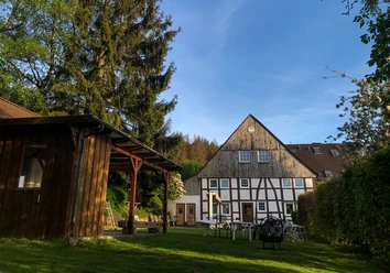 Naturfreundehaus Außenansicht Fachwerkhaus mit Garten und Bäumen, kombiniert traditionelle Architektur und grüner Außenbereich.