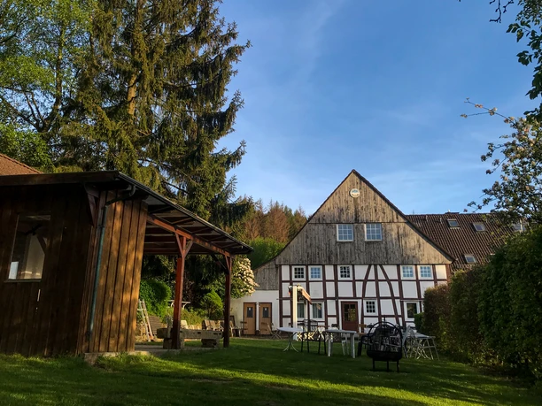 Naturfreundehaus Außenansicht Fachwerkhaus mit Garten und Bäumen, kombiniert traditionelle Architektur und grüner Außenbereich.