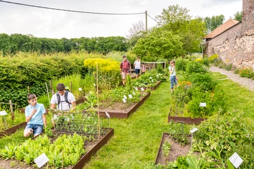 Kräutergarten der Biologischen Station von Haus Bürgel in Monheim am Rhein Besucher:innen erkunden gepflegte Kräuterbeete in einem weitläufigen Garten, umgeben von Natur.