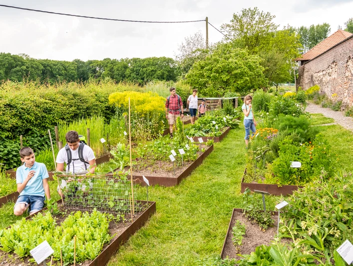 Kräutergarten der Biologischen Station von Haus Bürgel in Monheim am Rhein Besucher:innen erkunden gepflegte Kräuterbeete in einem weitläufigen Garten, umgeben von Natur.