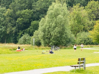 Grüne Wiesen im Freizeitraum Große Aue. Menschen relaxen und Spaziergänger genießen die Natur.