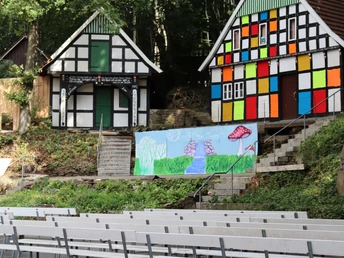 Freilichtbühne Kahle Wart mit bunten Fachwerkhäusern und Sitzreihen in einer Waldkulisse.
