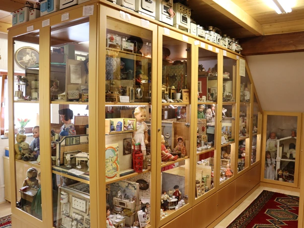 Spielzeugmuseum mit Vitrinen voller klassischer Puppen, Blechspielzeug und historischen Modellen.