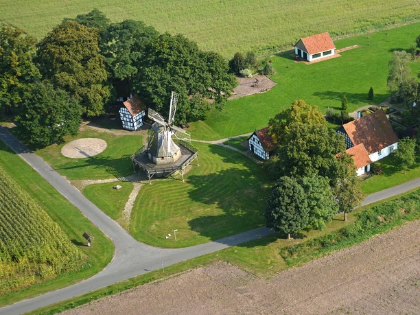 Kolthoffsche Mühle Levern Luftbild einer historischen Windmühle im Fachwerkstil, umgeben von grüner Wiese und Gebäuden.