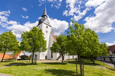 Stiftskirche Levern Weiße Stiftskirche Levern mit markantem Turm, umgeben von grünen Bäumen und blauem Himmel.