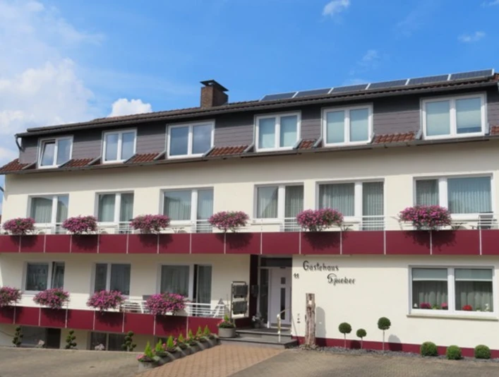 Ein zweistöckiges Gästehaus mit Blumen verzierten Fenstern und einem einladenden Eingangsbereich.