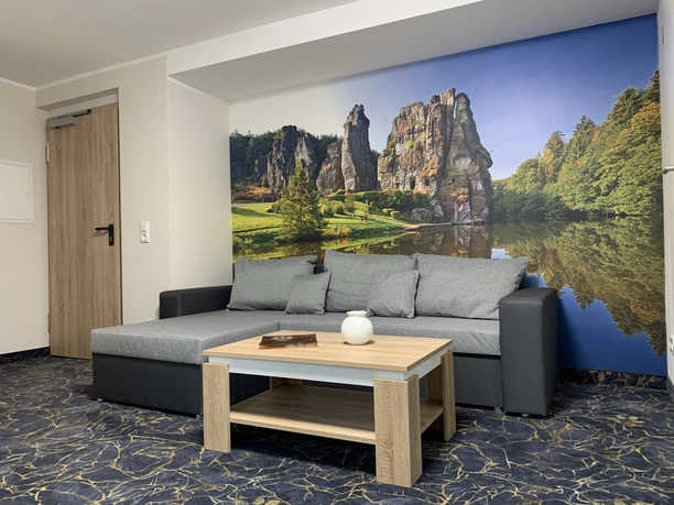 Appartment Appartement mit grauem Sofa und Couchtisch, im Hintergrund großflächiges Wandbild einer Felslandschaft.