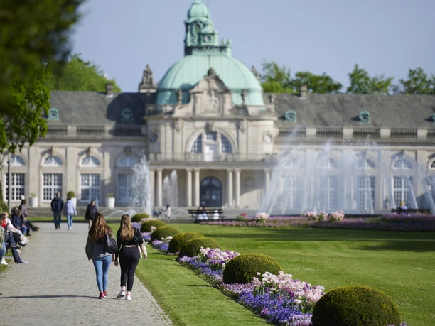 Kaiserpalais Zwei Frauen spazieren auf einem Weg vor dem Kaiserpalais, umgeben von Springbrunnen und Gärten.