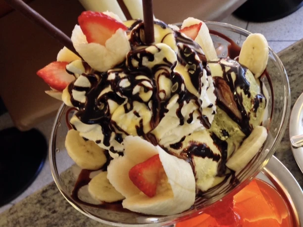 Ein köstlicher Dessertbecher mit Vanilleeis, überzogen mit Schokosoße, Erdbeeren und Bananenscheiben.