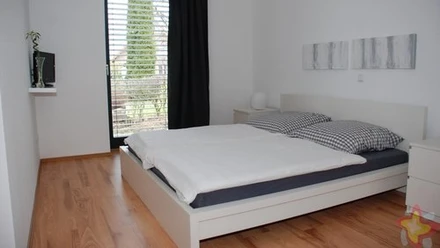 Helles Schlafzimmer mit Doppelbett, Holzboden, modernem Dekor und einem Fenster mit Ausblick.