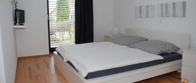Helles Schlafzimmer mit Doppelbett, Holzboden, modernem Dekor und einem Fenster mit Ausblick.