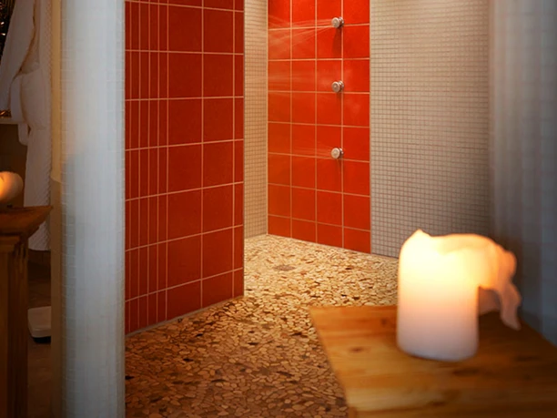 Wellnessbereich Kerzen erleuchten eine moderne Wellnessdusche mit roten Fliesen und pebble Boden, strahlend einladend.