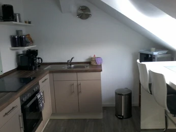 Ferienwohnung Carpe Diem Küche Helle Küche unter einer Dachschräge, mit modernen Geräten, Spüle, Arbeitsfläche und Essecke.