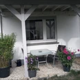 Ferienwohnung Carpe Diem Außenbereich Überdachte Terrasse der Ferienwohnung Carpe Diem mit Tisch, Stühlen und Topfpflanzen in blühender Umgebung.