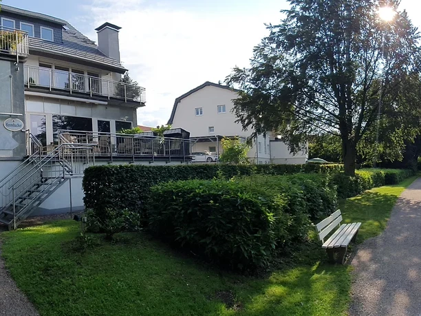 Das Restaurant "Blaues", ein Gebäude mit Terrasse, liegt direkt an einem ruhigen Flussweg umgeben von Bäumen.
