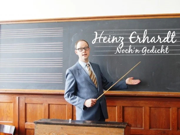 Mann in Anzug mit Brille präsentiert vor einer Tafel mit der Aufschrift "Heinz Erhardt - Noch 'n Gedicht".