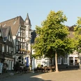 Kirchplatz der Oberstadt in Mettmann Historische Fachwerkgebäude und Bäume säumen den Kirchplatz in Mettmann bei klarem Himmel.