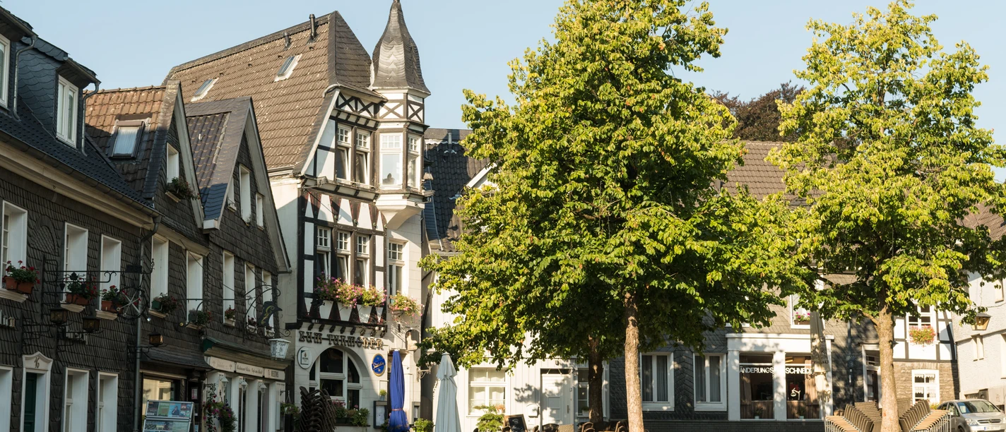 Kirchplatz der Oberstadt in Mettmann Historische Fachwerkgebäude und Bäume säumen den Kirchplatz in Mettmann bei klarem Himmel.