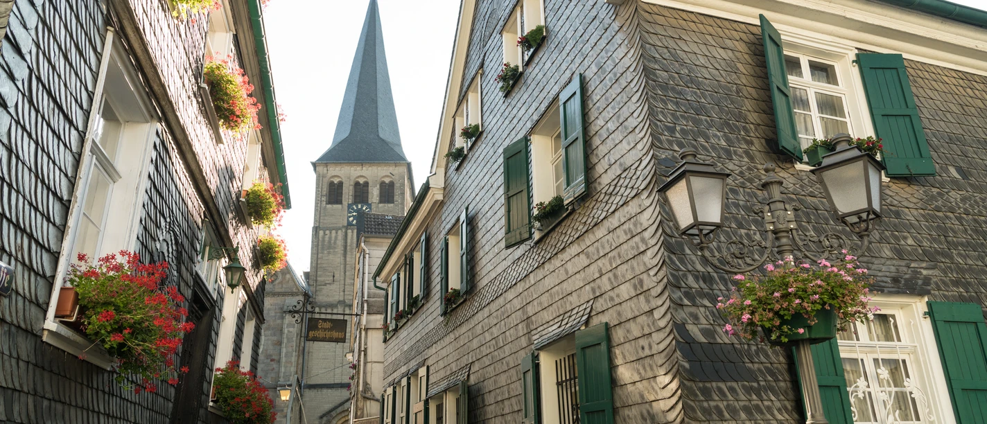 Oberstadt Mettmann mit Stadtgeschichtshaus und St. Lambertus Kirche Fachwerkhäuser mit Schieferfassaden und grünen Fensterläden in Mettmanns Oberstadt, St. Lambertus im Hintergrund.