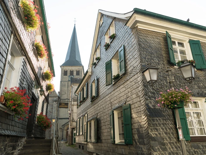 Oberstadt Mettmann mit Stadtgeschichtshaus und St. Lambertus Kirche Fachwerkhäuser mit Schieferfassaden und grünen Fensterläden in Mettmanns Oberstadt, St. Lambertus im Hintergrund.
