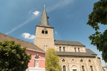 Reformationskirche zu Hilden Eine imposante Reformationskirche mit hoch aufragendem Turm und umliegenden historischen Gebäuden.