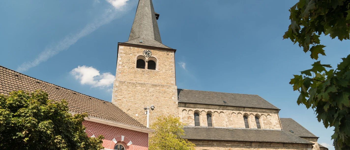 Reformationskirche zu Hilden Eine imposante Reformationskirche mit hoch aufragendem Turm und umliegenden historischen Gebäuden.