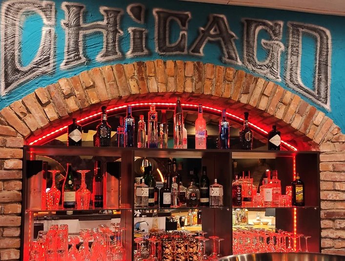 Vitrine in einer Bar, hier sind Gläser und Flaschen unter dem Schriftzug "Chicago" zu sehen