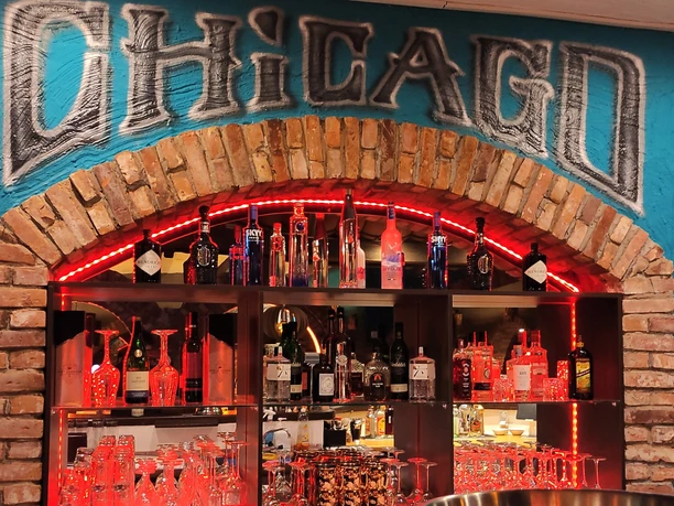Chicago Burger Bar Vitrine in einer Bar, hier sind Gläser und Flaschen unter dem Schriftzug "Chicago" zu sehen