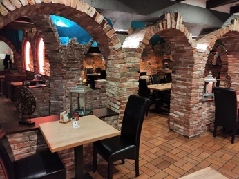 Ein Gastraum in einem Restaurant mit Stühlen, Tischen und gemauerten Bögen aus Backsteinen,